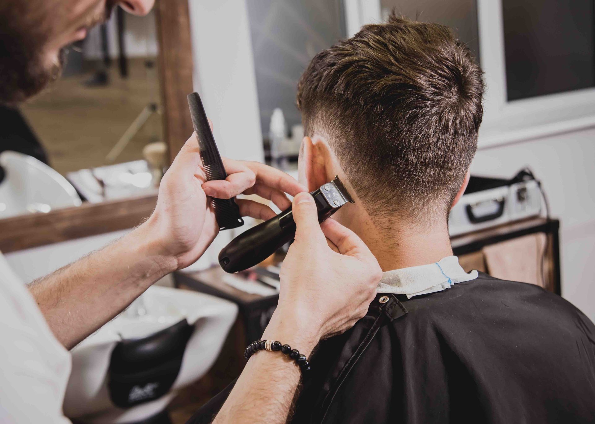 A man is getting his hair cut by a barber in a barber shop.