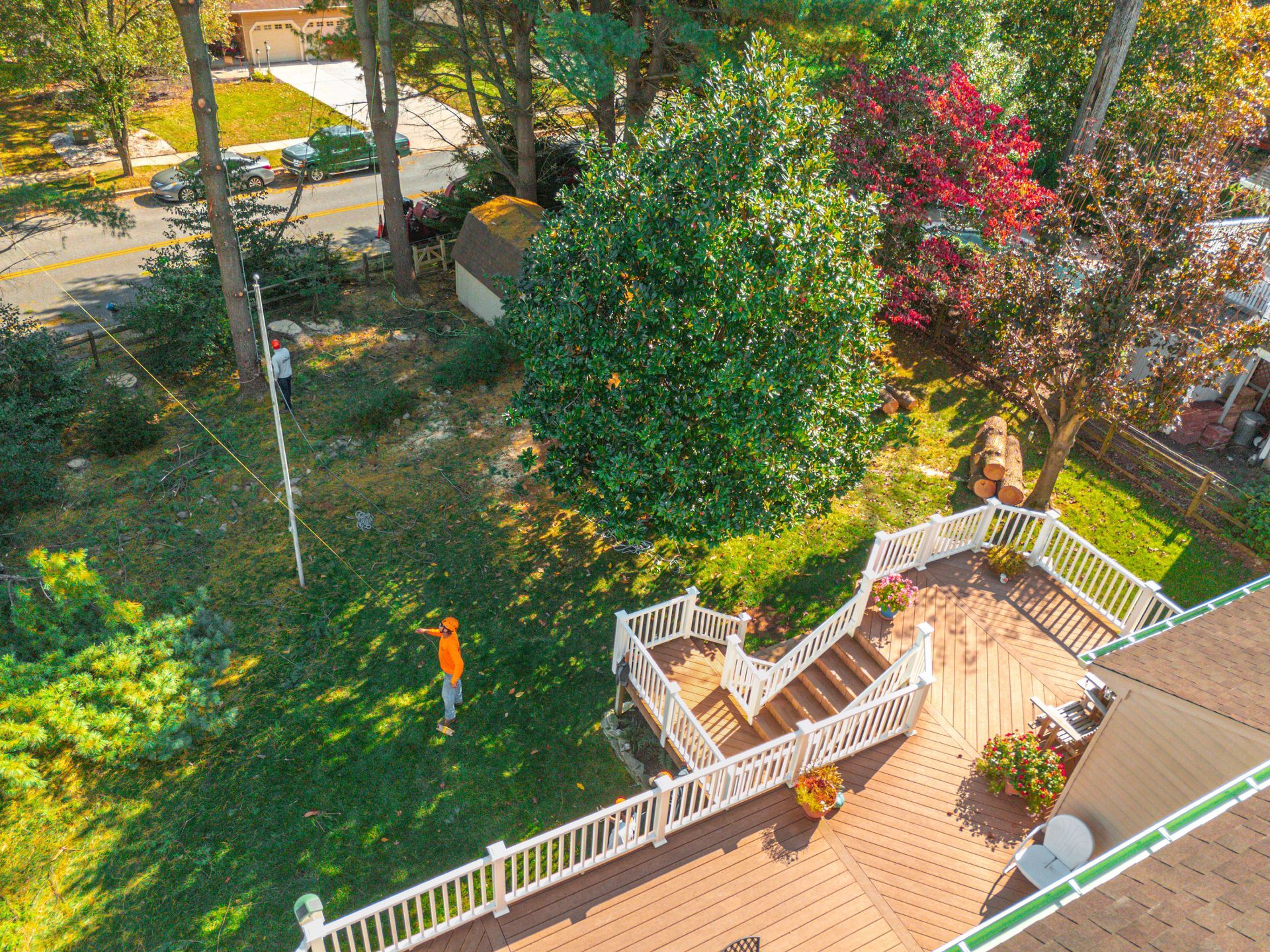 Overhead view of a deck and yard with a person, tree, and surrounding houses.