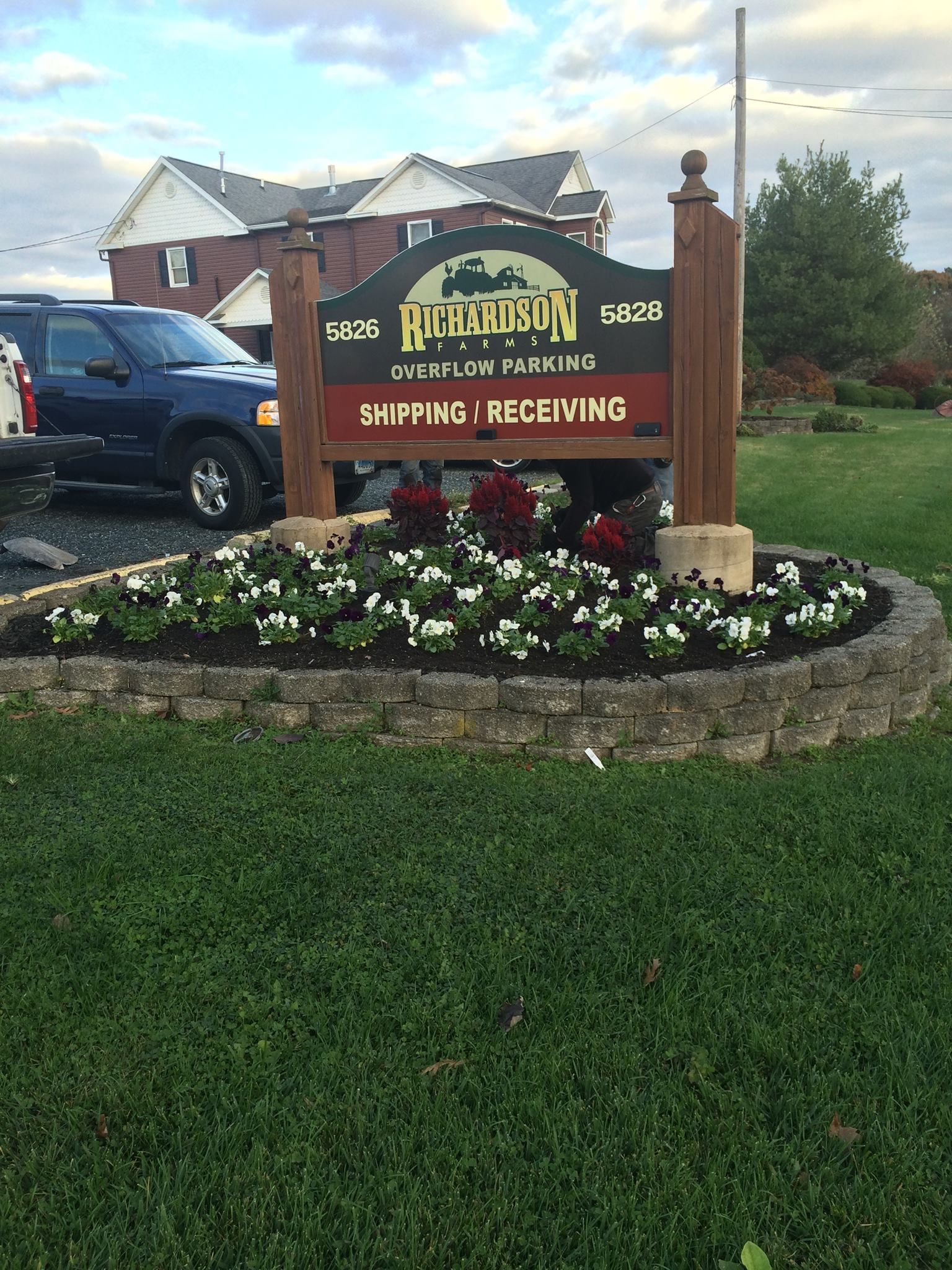 Sign for Pleasant Hills, PA, with a flower bed and a truck in front of a building.