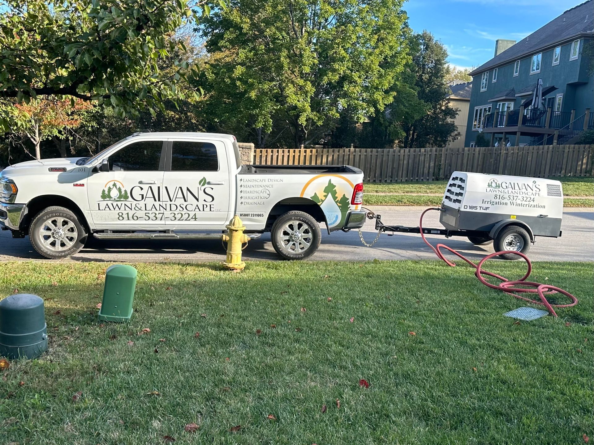 White truck with trailer parked on grass, branded with 