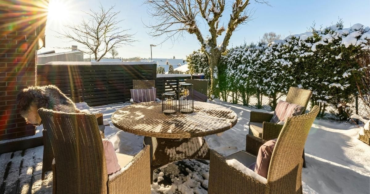 Snowy rooftop patio with wicker chairs around a round table in bright sunlight