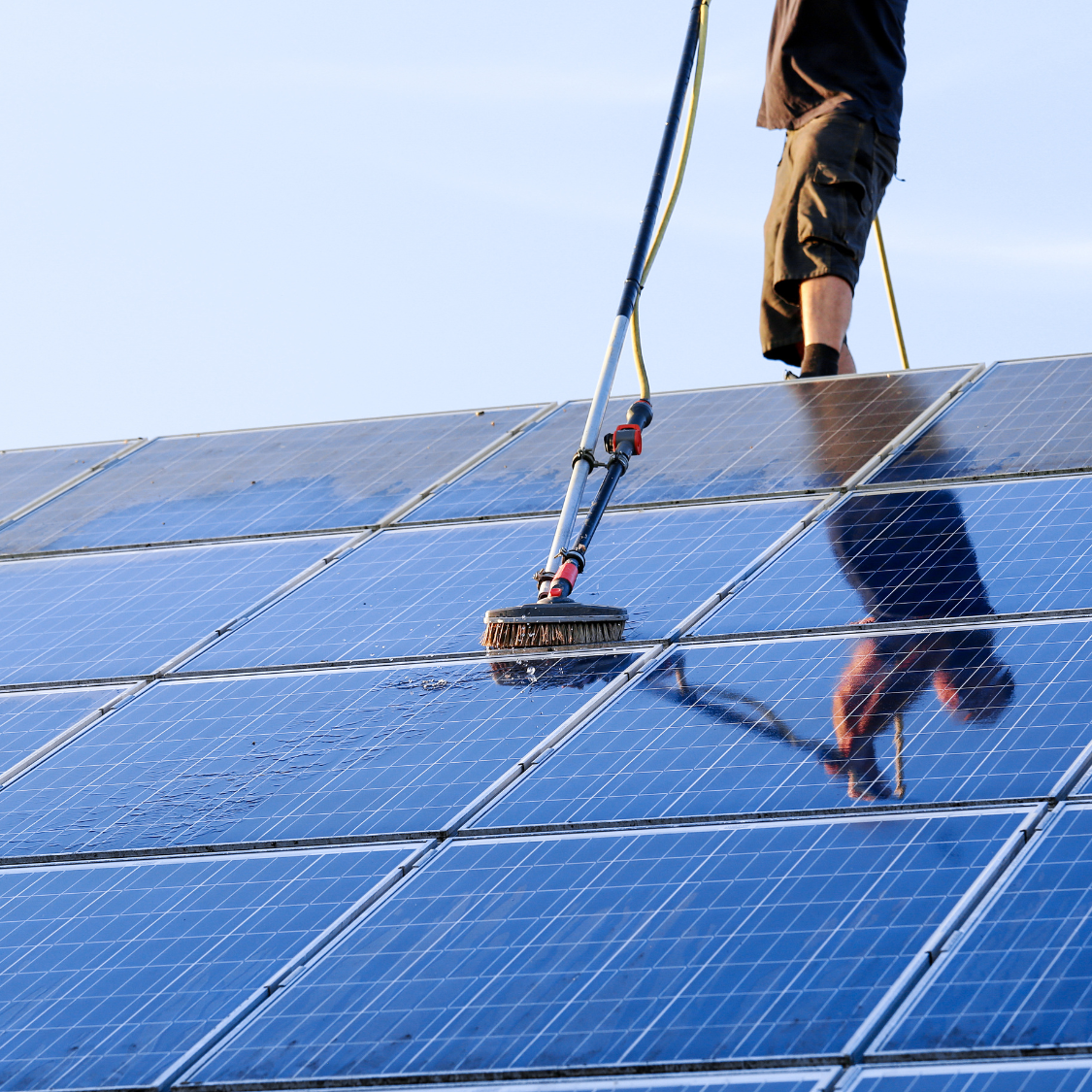 A man is cleaning a solar panel with a brush
