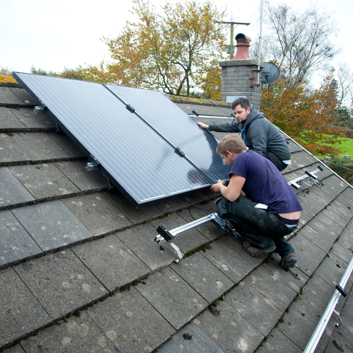Two men are working on a solar panel on a roof