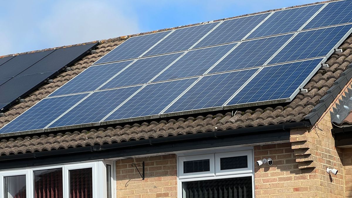 There are many solar panels on the roof of a house.
