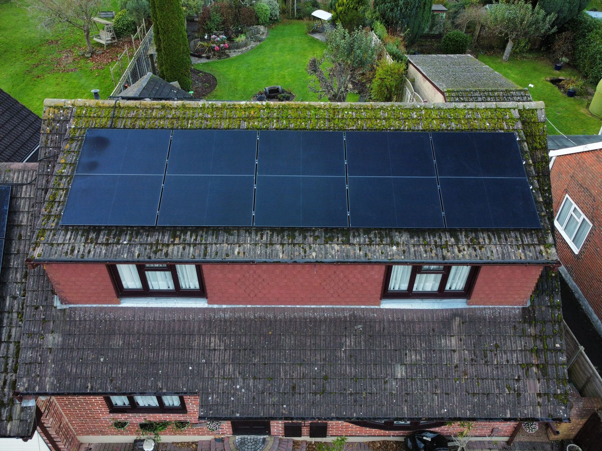 An aerial view of a house with solar panels on the roof.