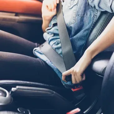 Persona en el coche abrochándose el cinturón de seguridad.