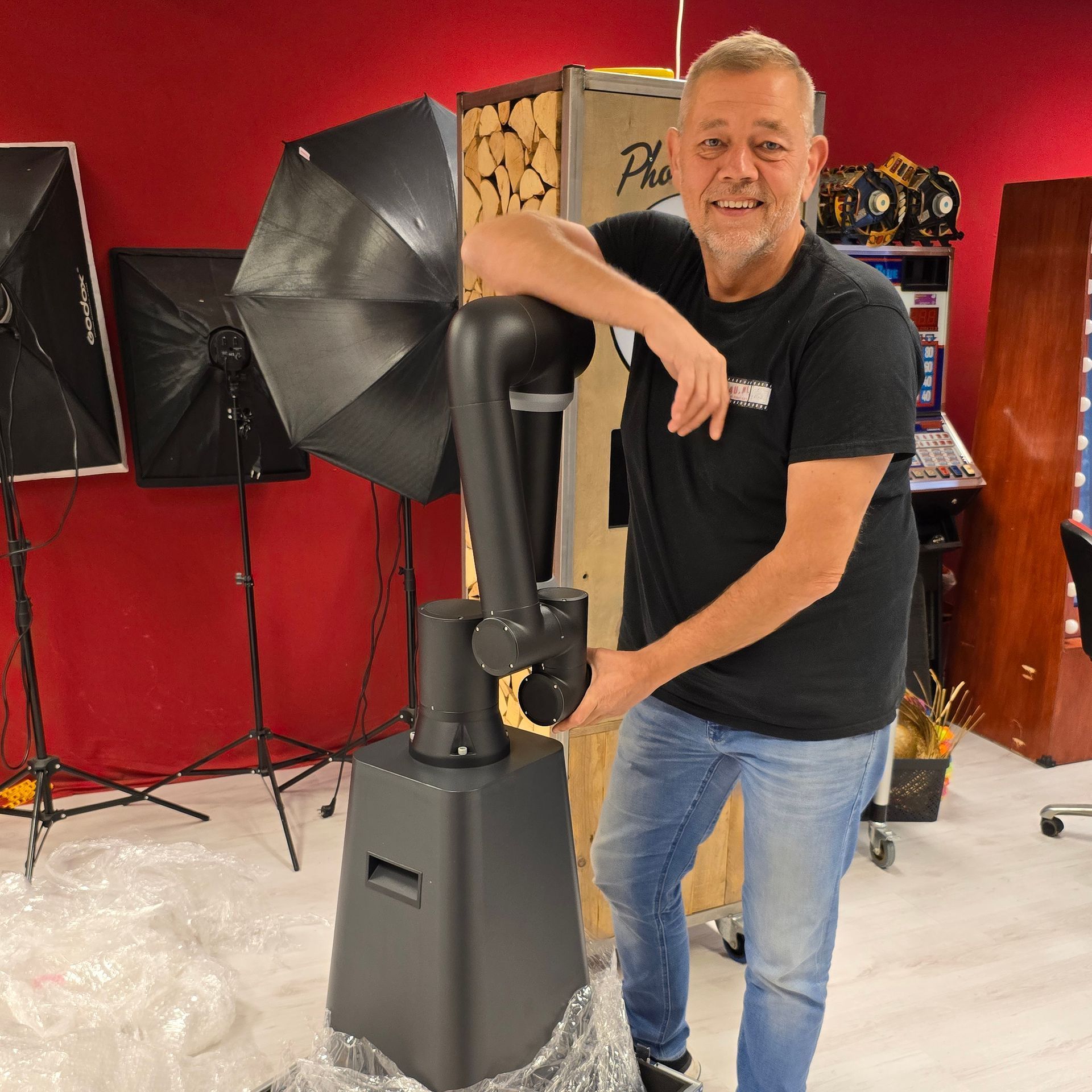 Man in zwart shirt en spijkerbroek met camerarobot in een studio-omgeving.