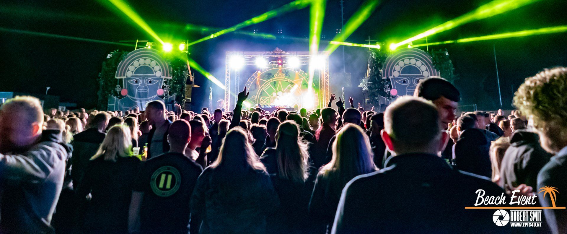 Publiek bij een concert met groene podiumverlichting.