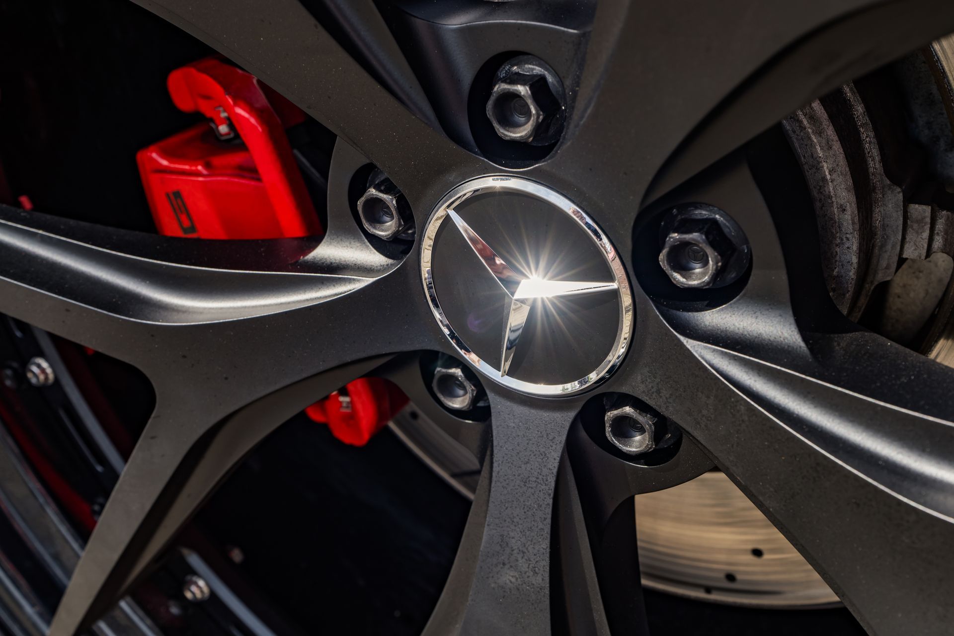 Close-up van een zwart Mercedes-Benz wiel met het logo in het midden en rode remklauwen.
