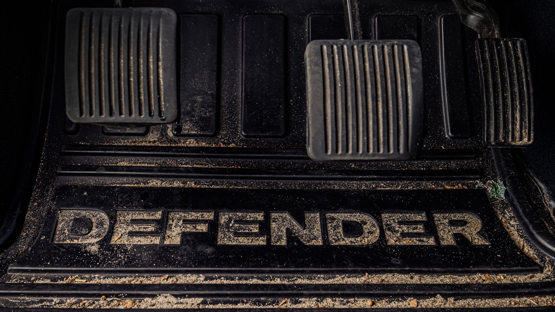 Close-up van de voetenruimte van een Land Rover Defender met pedalen en het 