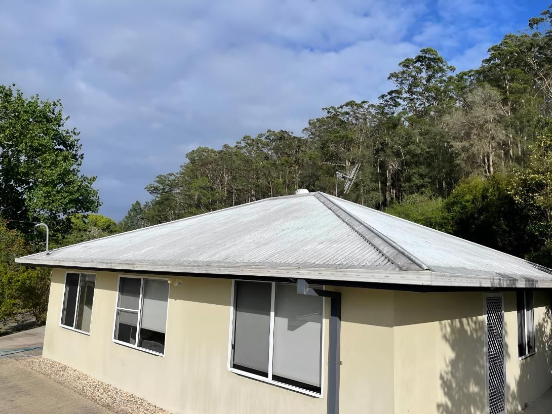Small House With a White Roof is Surrounded by Trees — Hastings Services in Port Macquarie, NSW