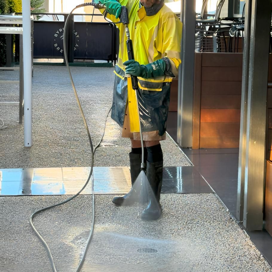 Man in a Yellow Jacket is Using a High Pressure Washer — Hastings Services in Port Macquarie, NSW