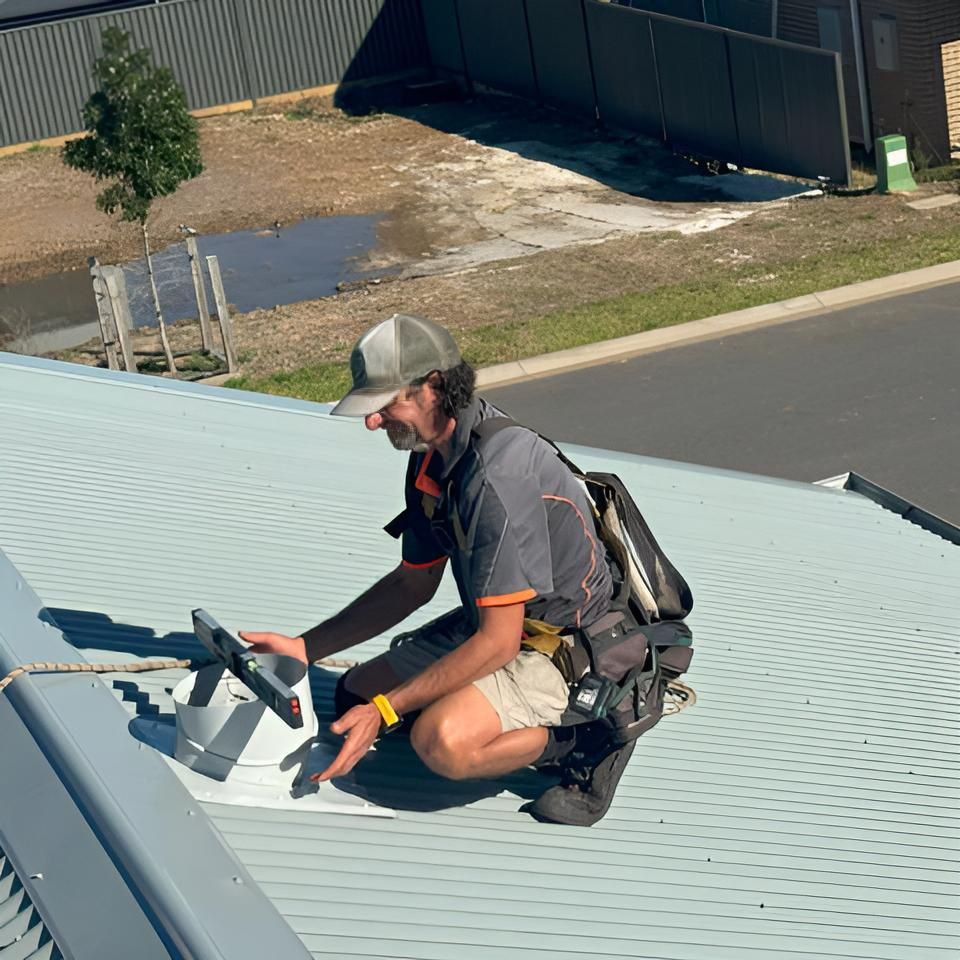 Man is Kneeling on the Roof of a Building — Hastings Services in Port Macquarie, NSW