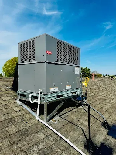 Gray rooftop air conditioning unit on a rooftop with a blue sky background.