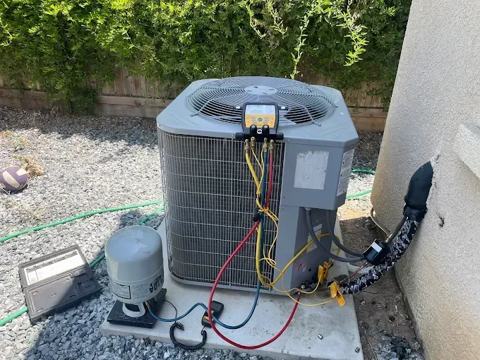 Outdoor air conditioning unit with wires connected and a gray pump on a concrete pad.