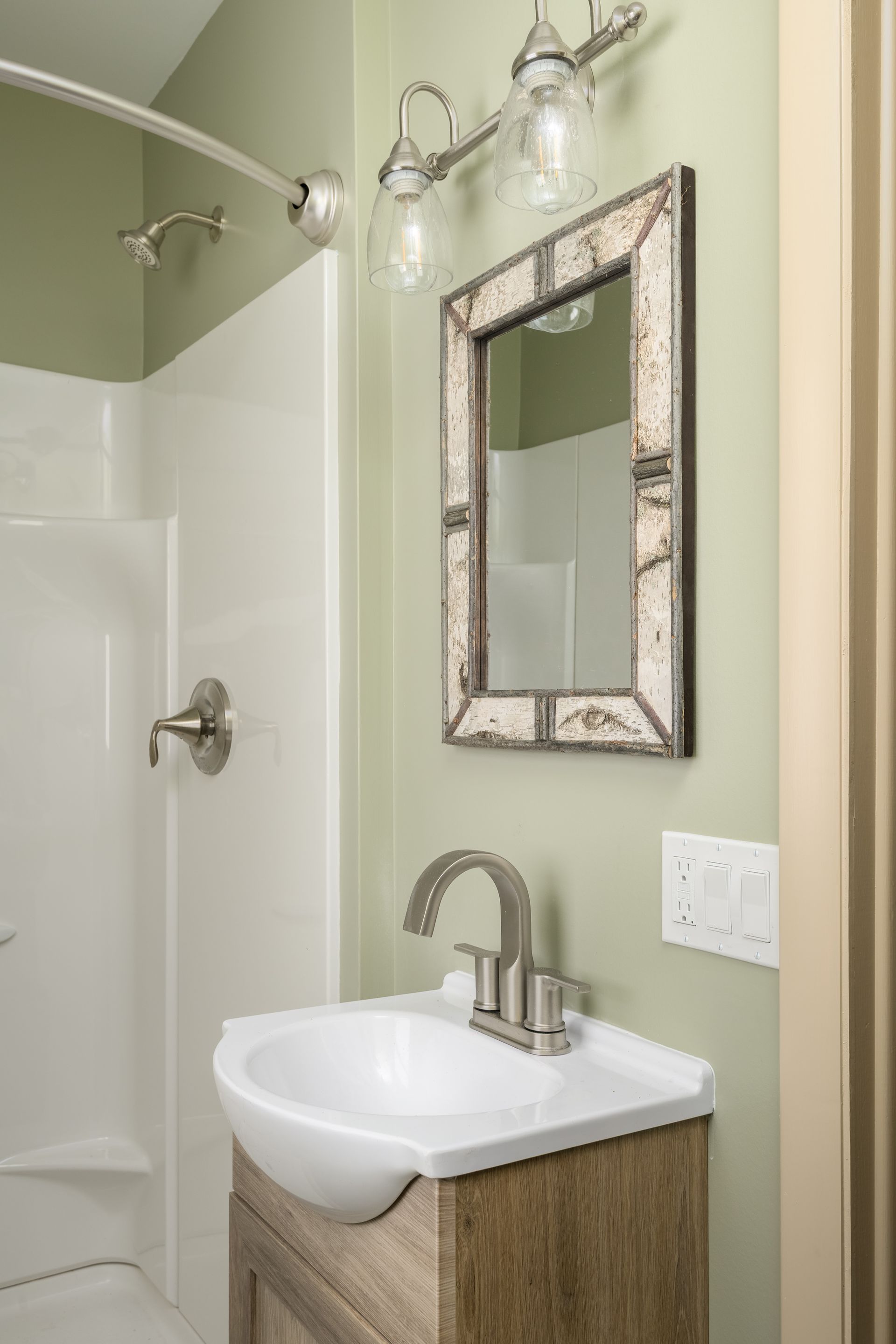 A bathroom with a sink , mirror and shower.