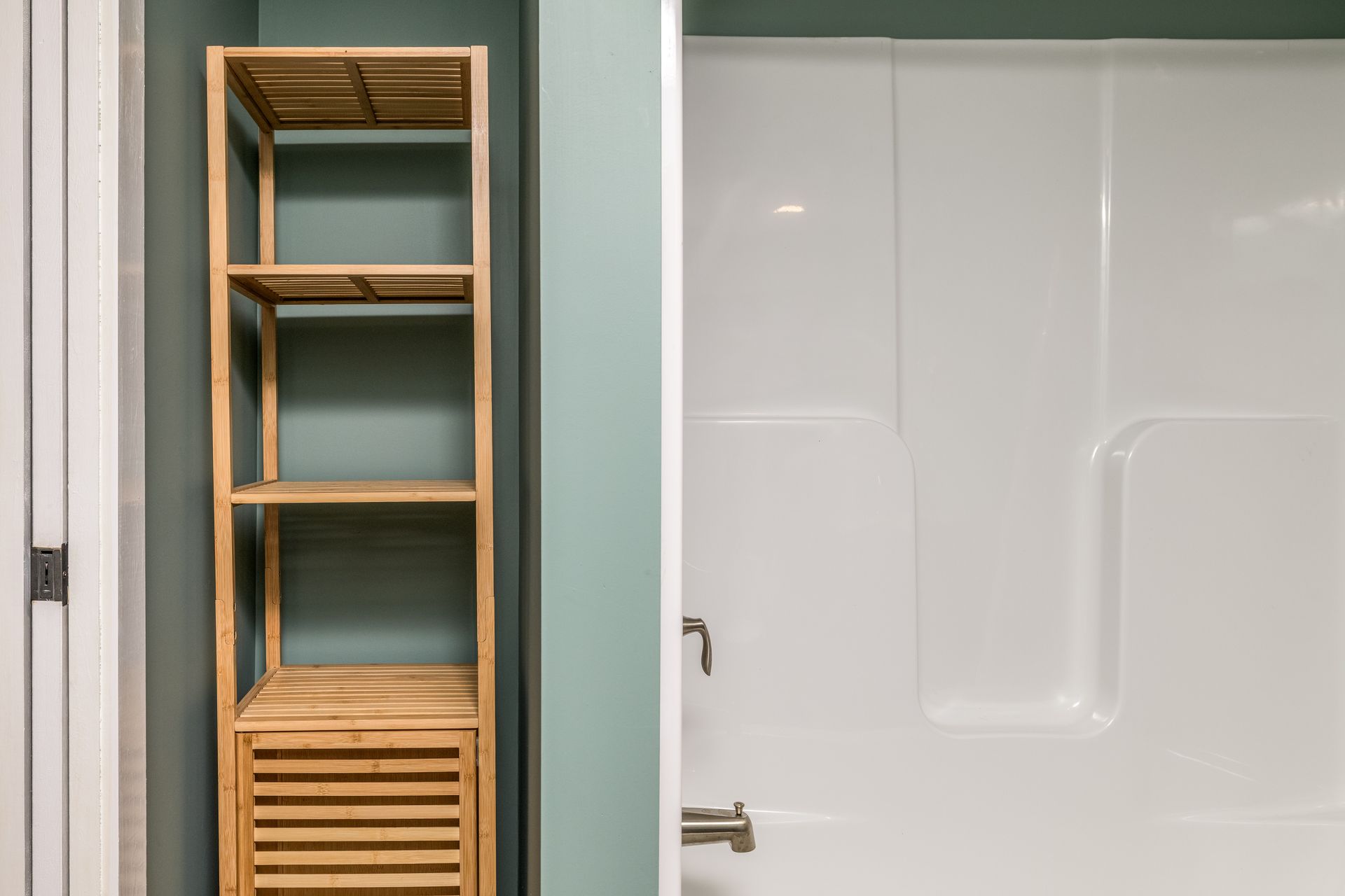 A bathroom with a wooden shelf and a white shower stall.