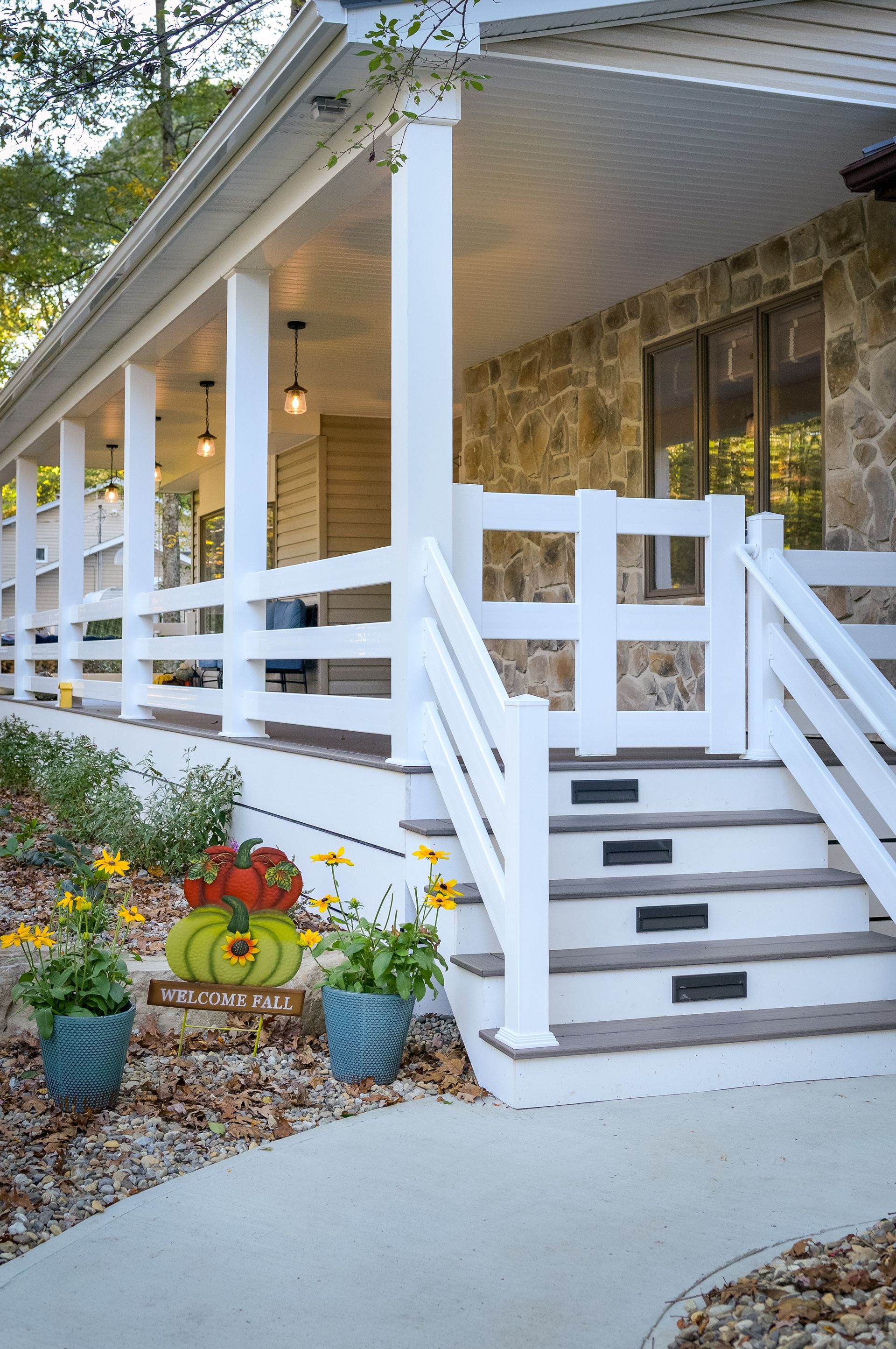 A wooden deck with black railing is being built in front of a house.