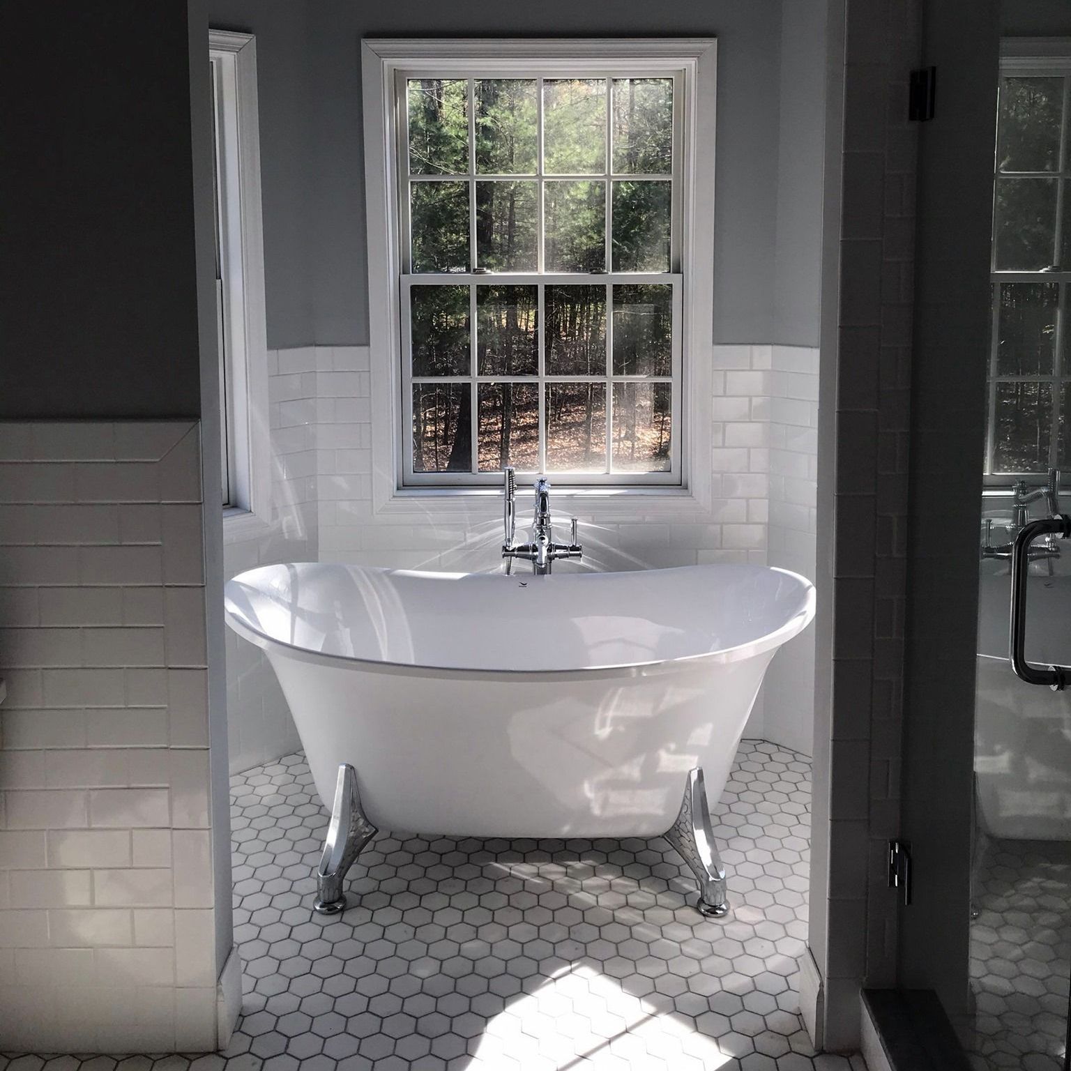 A bathtub in a bathroom next to a window
