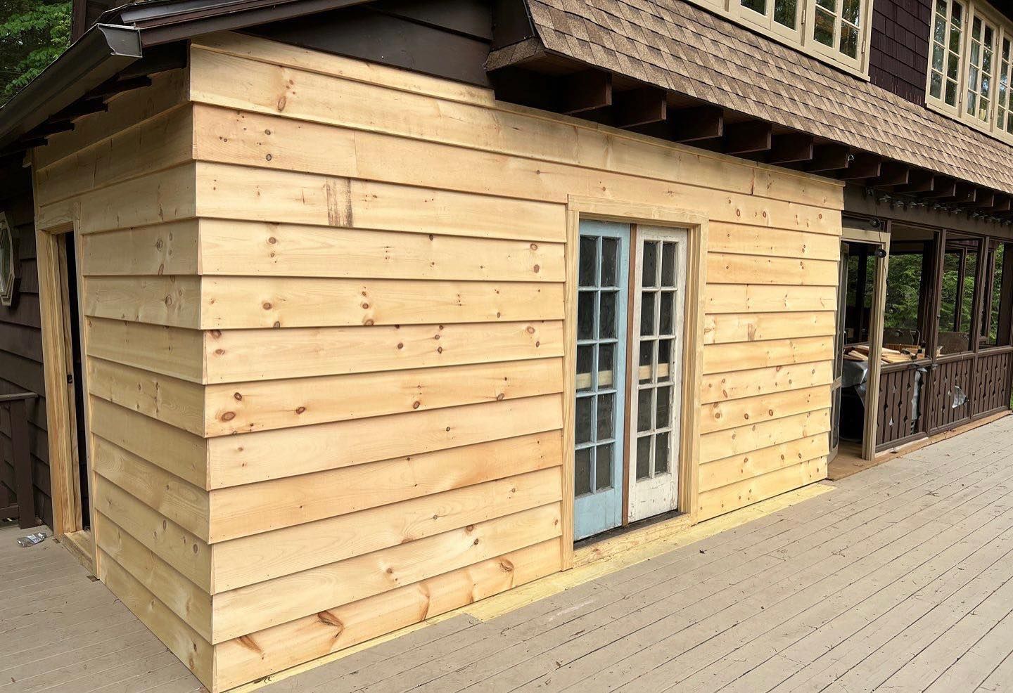 A wooden house with a porch and sliding glass doors.