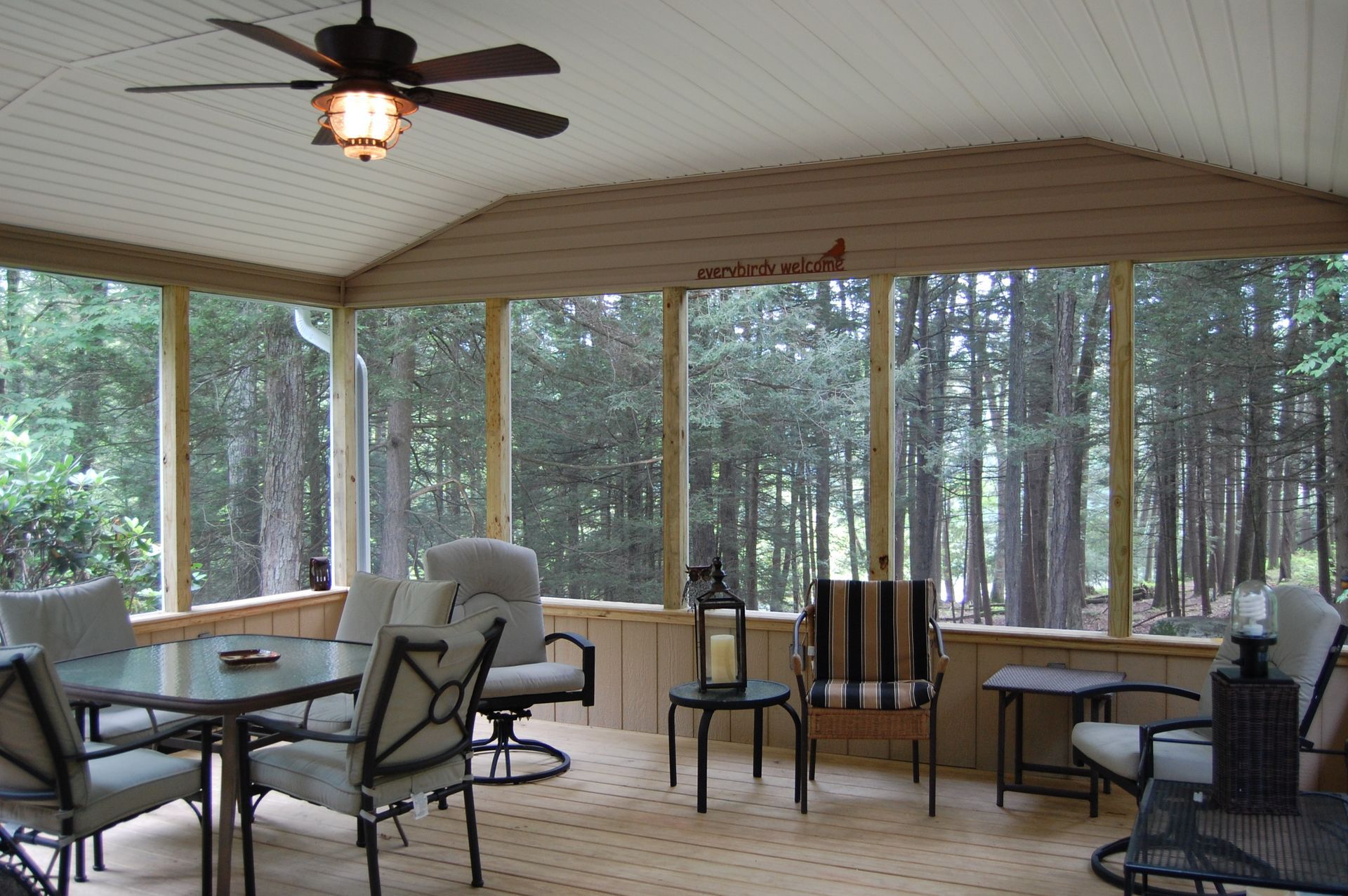 A screened in porch with a table and chairs and a ceiling fan