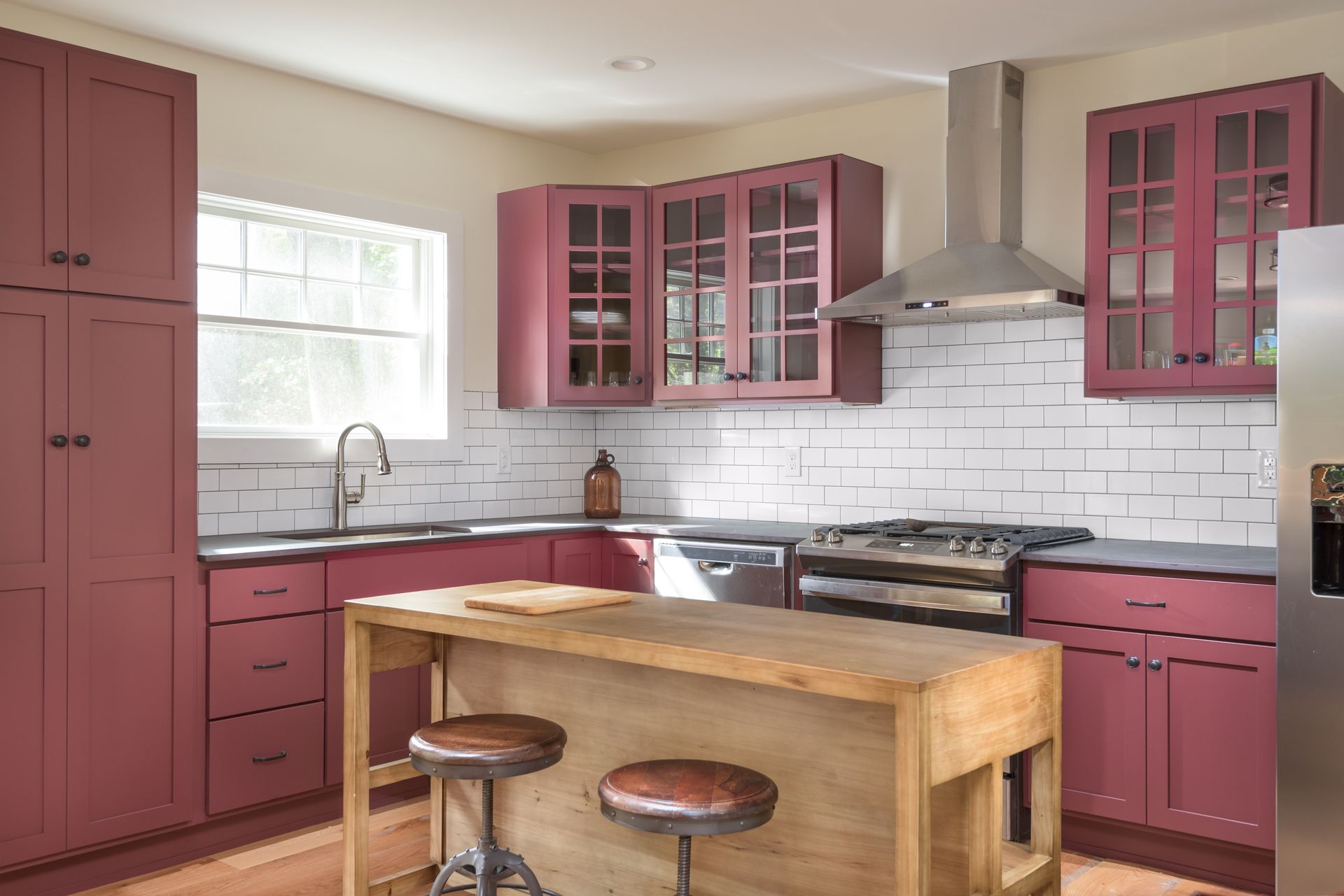 A kitchen with pink cabinets , stainless steel appliances , and a wooden island.