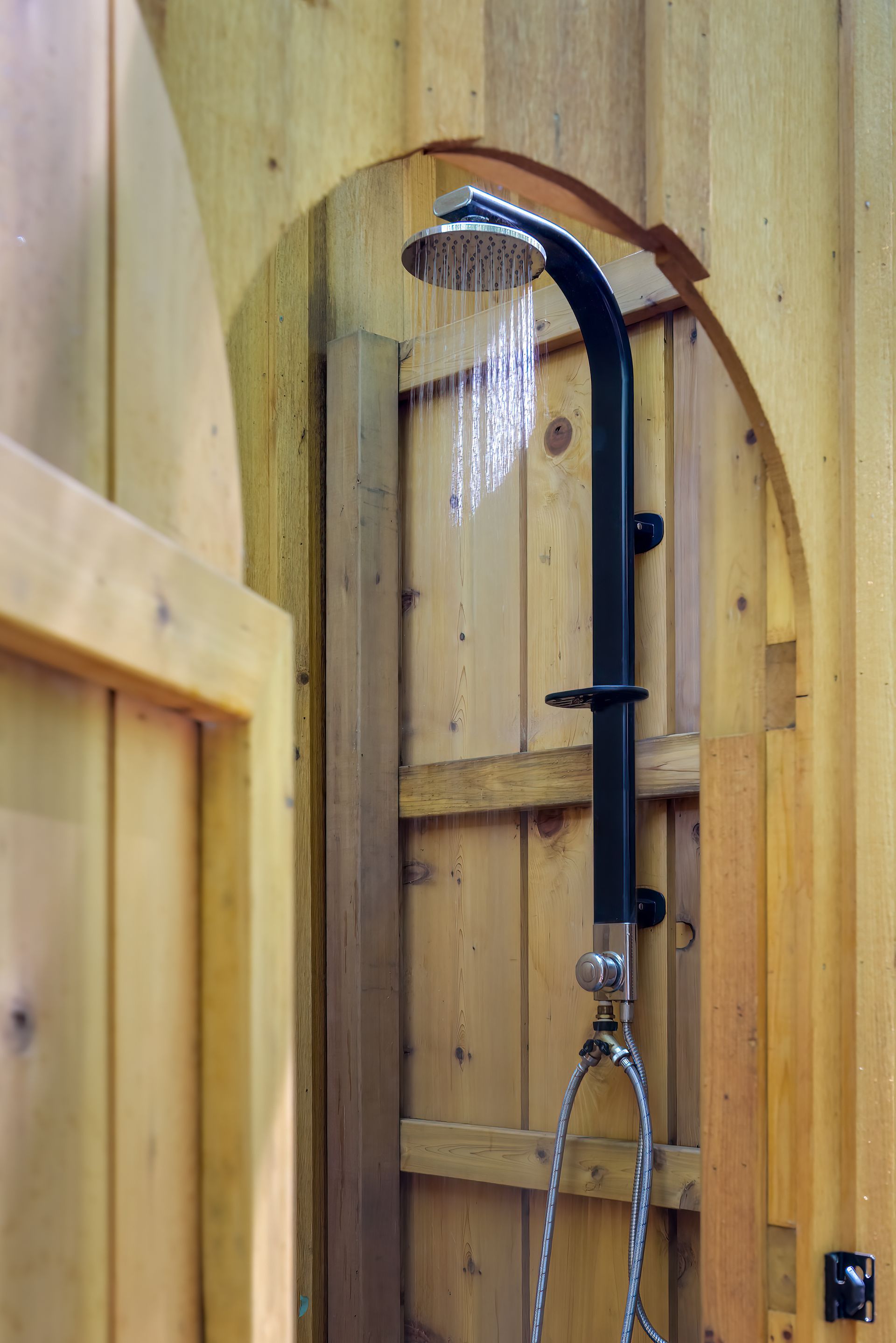 A wooden shower stall with a black shower head