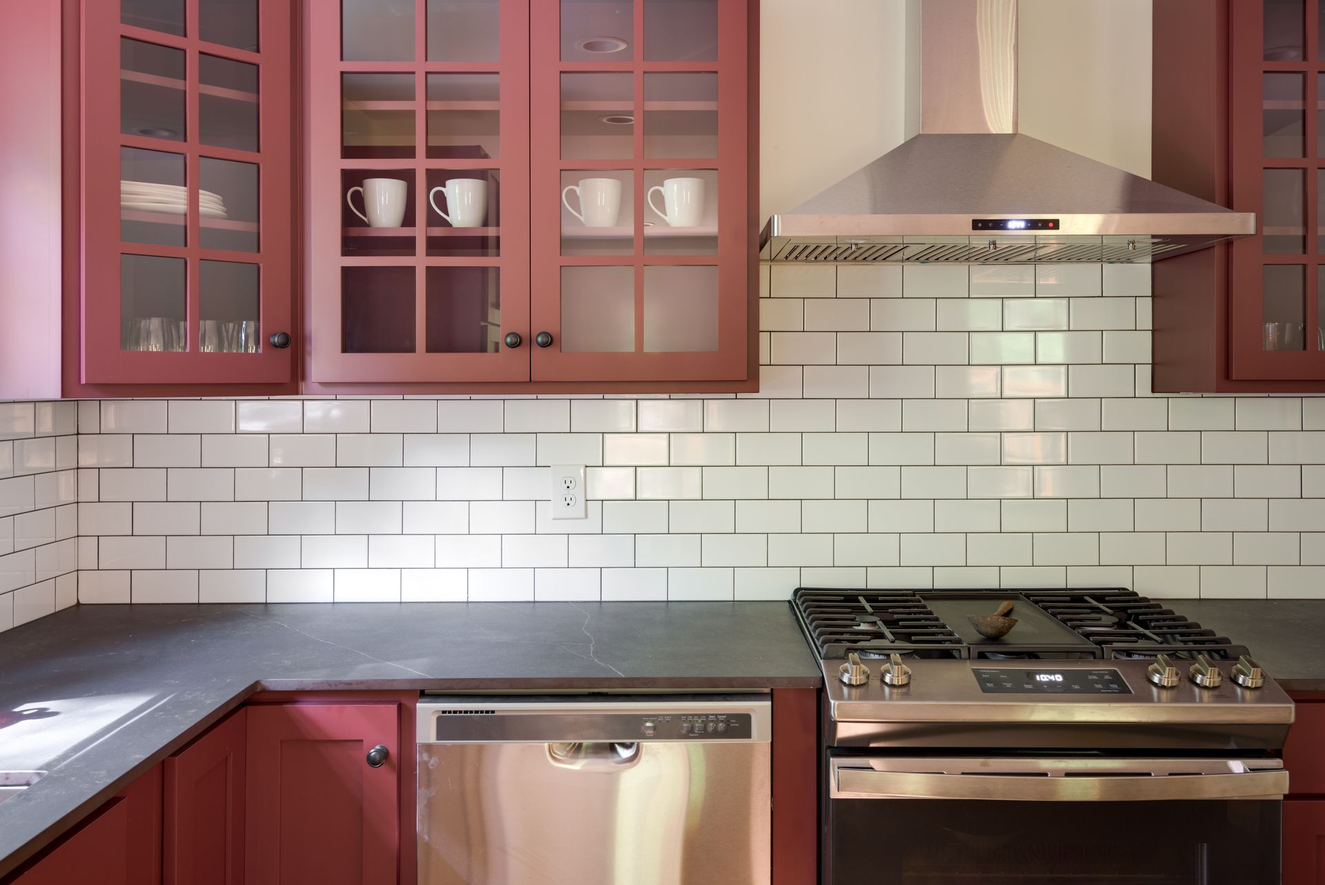 A kitchen with red cabinets and stainless steel appliances