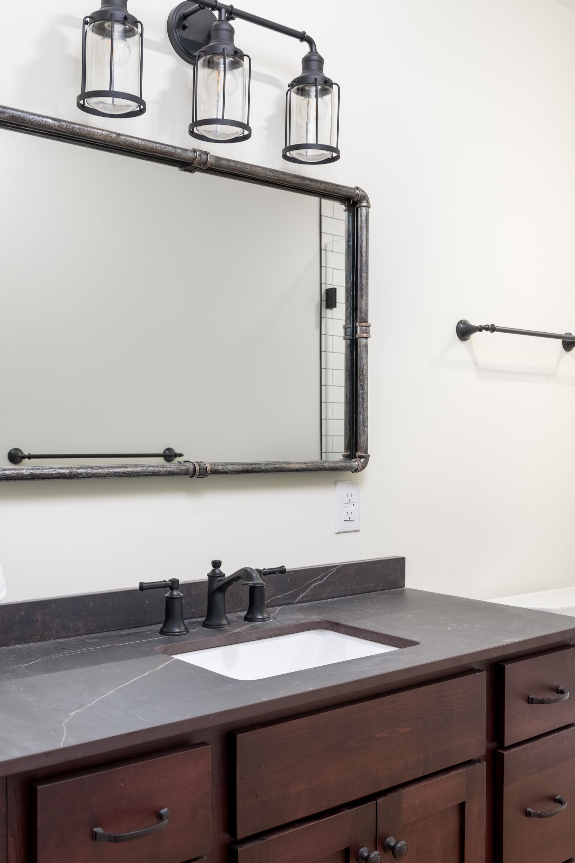 A bathroom with a sink , mirror and towel rack.