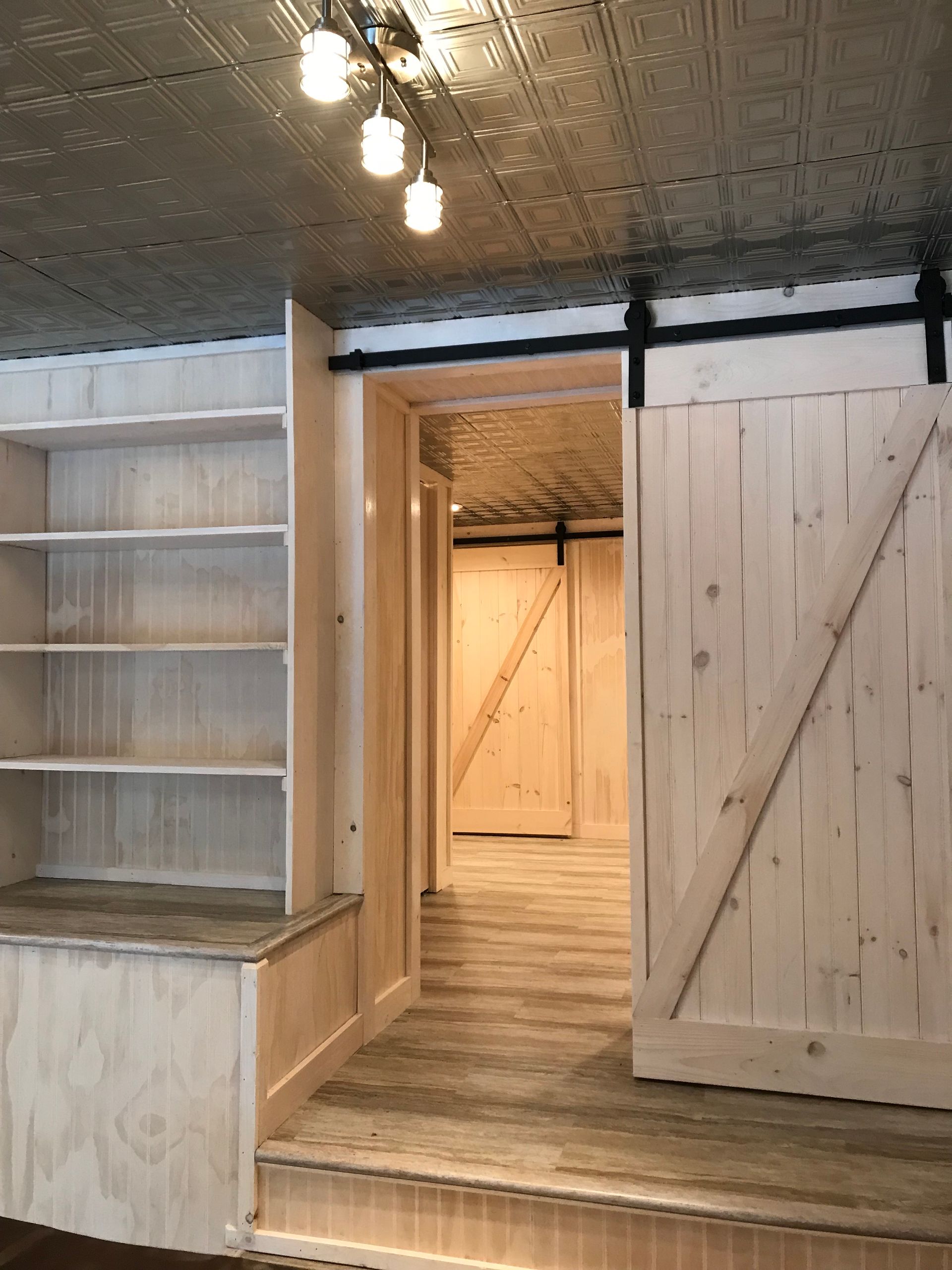 A room with a sliding barn door and shelves.