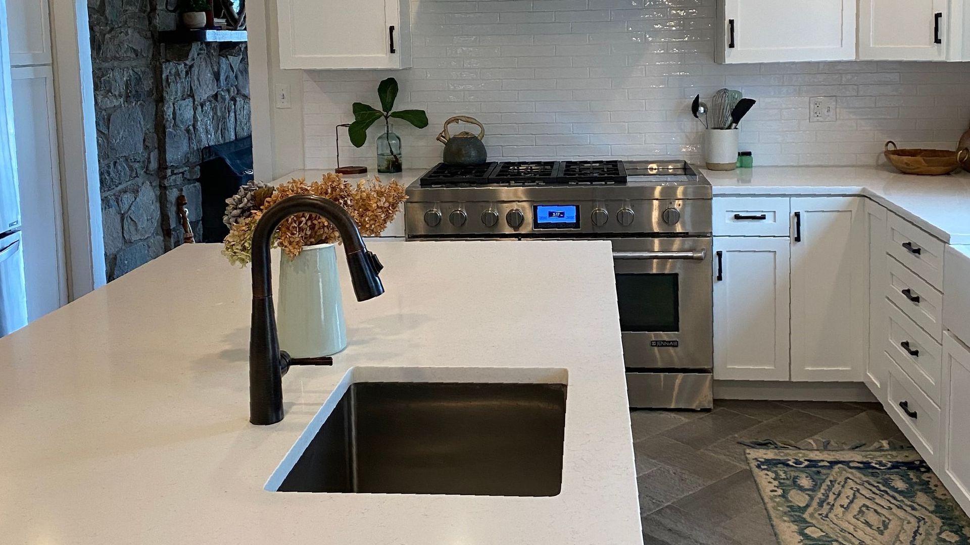 A kitchen with white cabinets , stainless steel appliances , a sink and a stove.