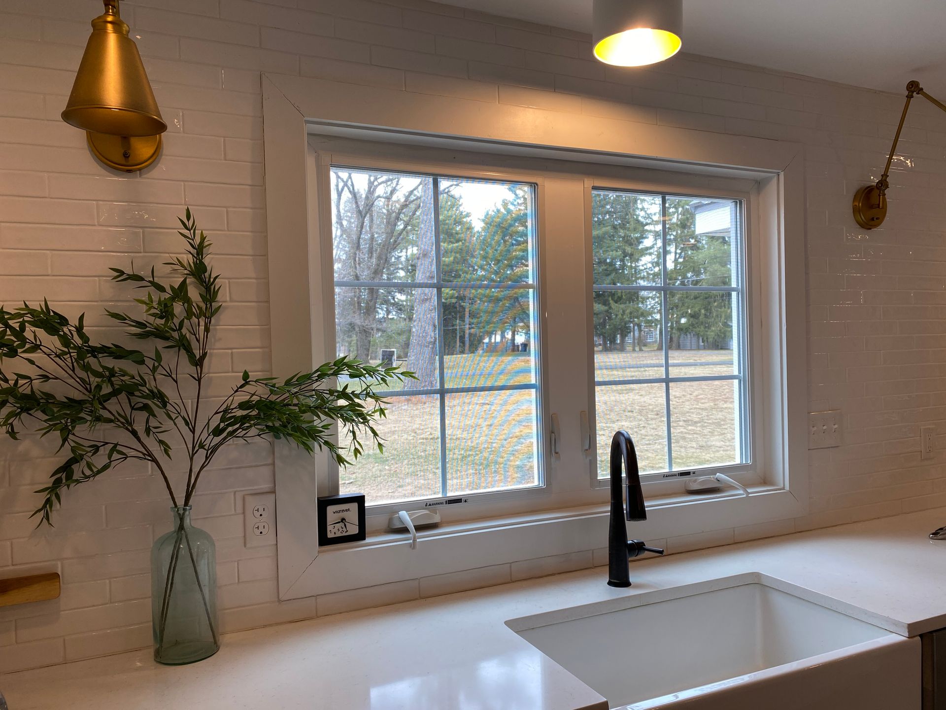 A kitchen with a sink and a window with a view of a field.