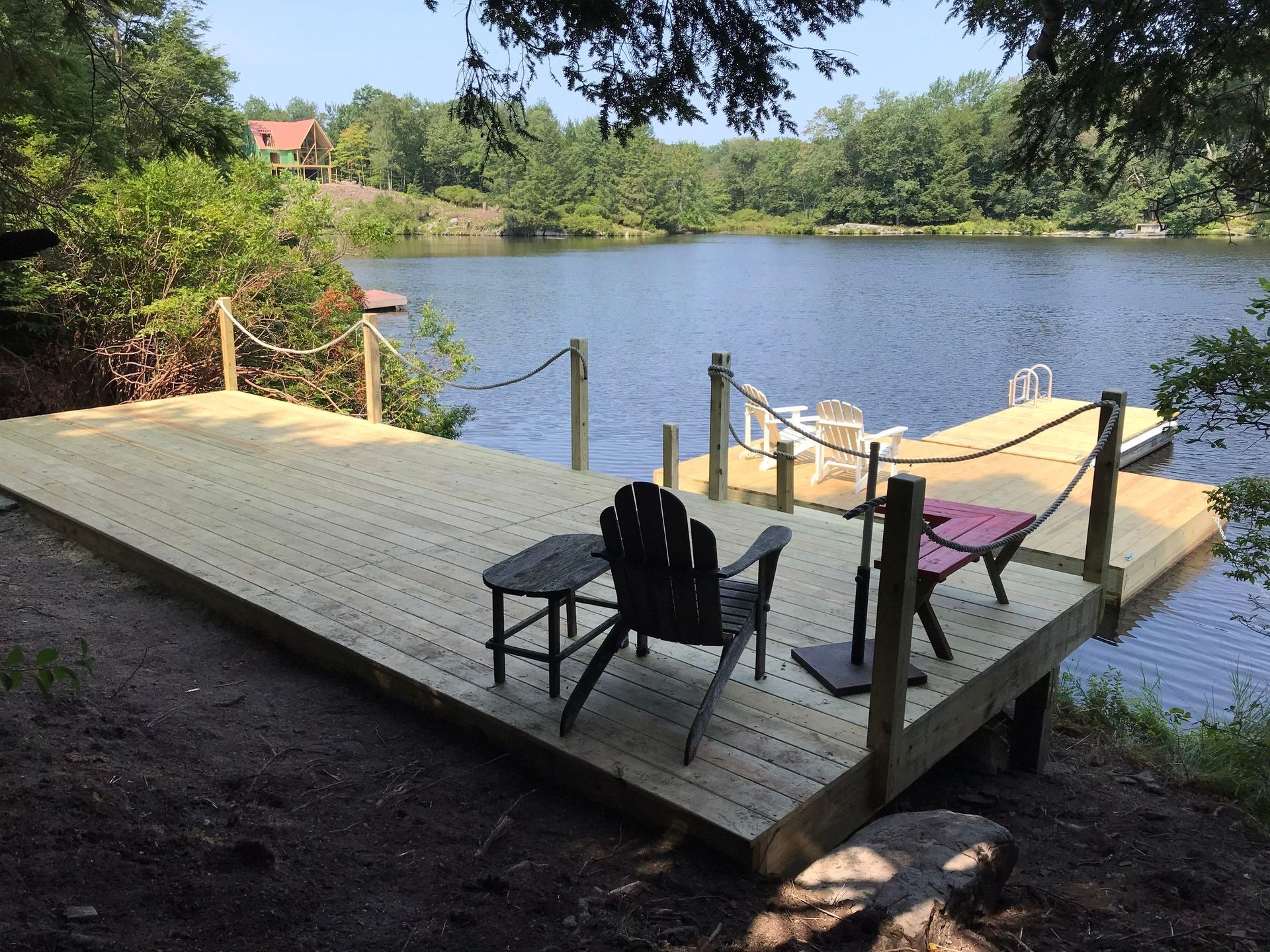 A wooden dock with chairs and a table overlooking a lake