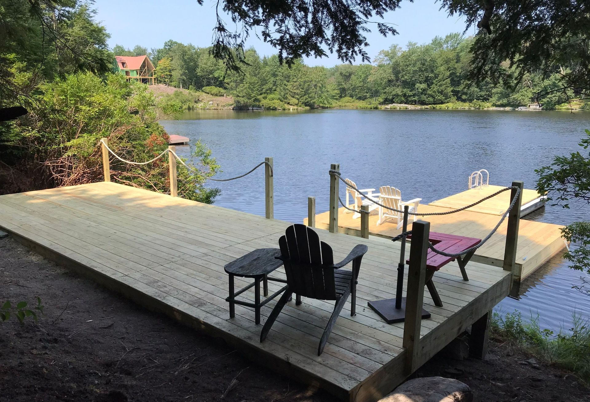 A wooden dock with chairs and a table overlooking a lake