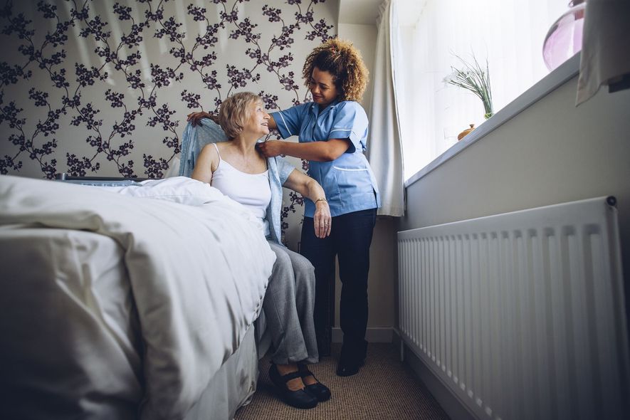 caregiver putting clothes on her patient