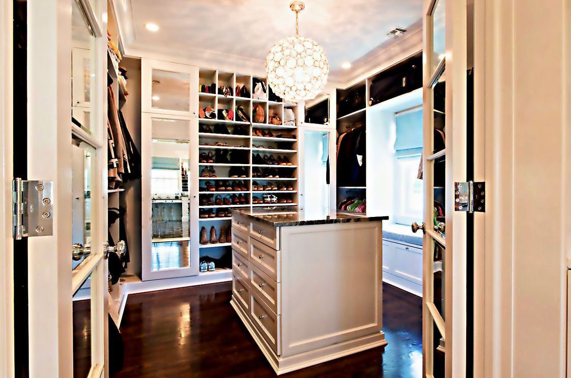 A large walk in closet with a large island in the middle.