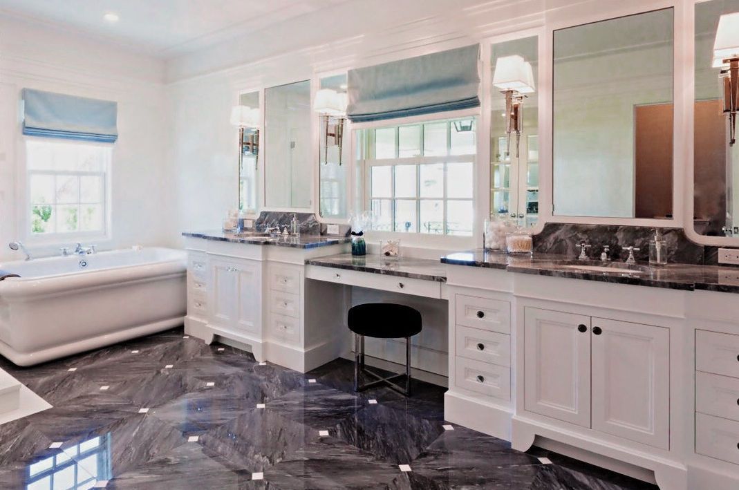 A bathroom with two sinks , a tub , and a vanity.