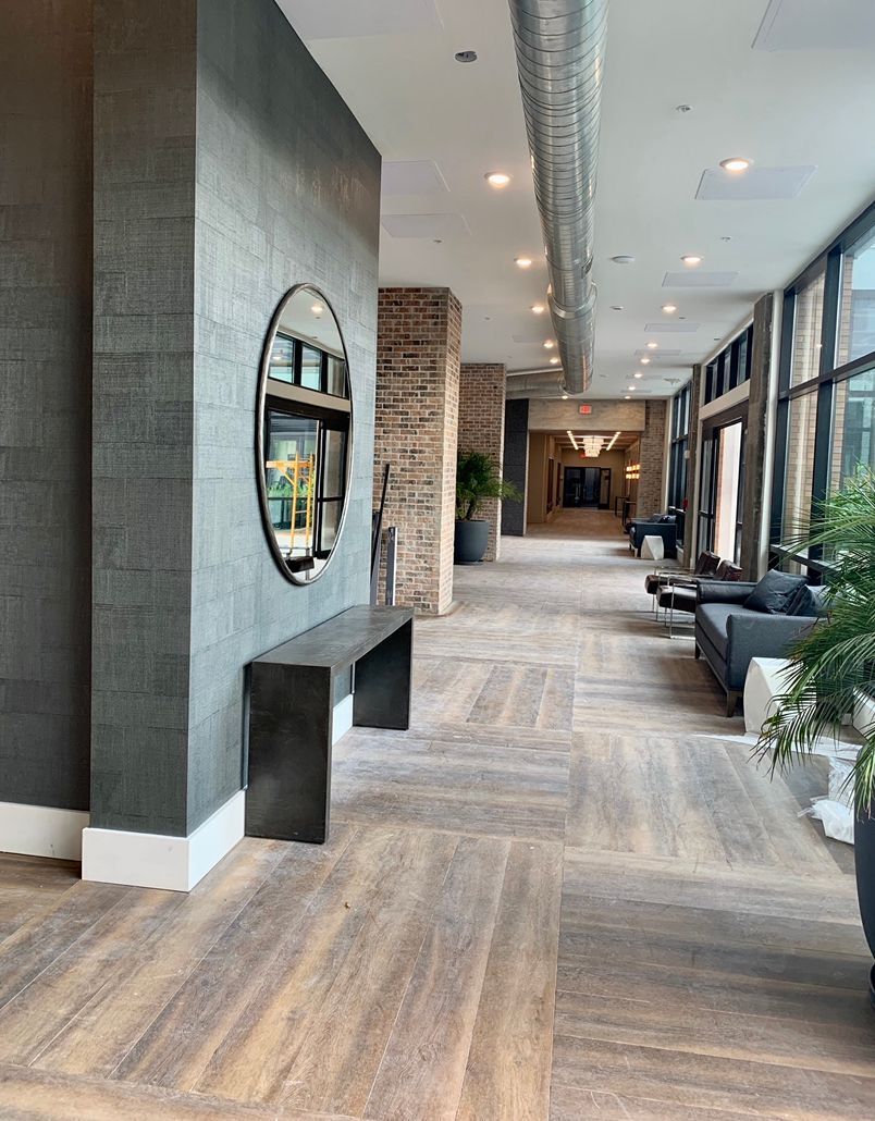 A long hallway with wooden floors and a mirror on the wall.
