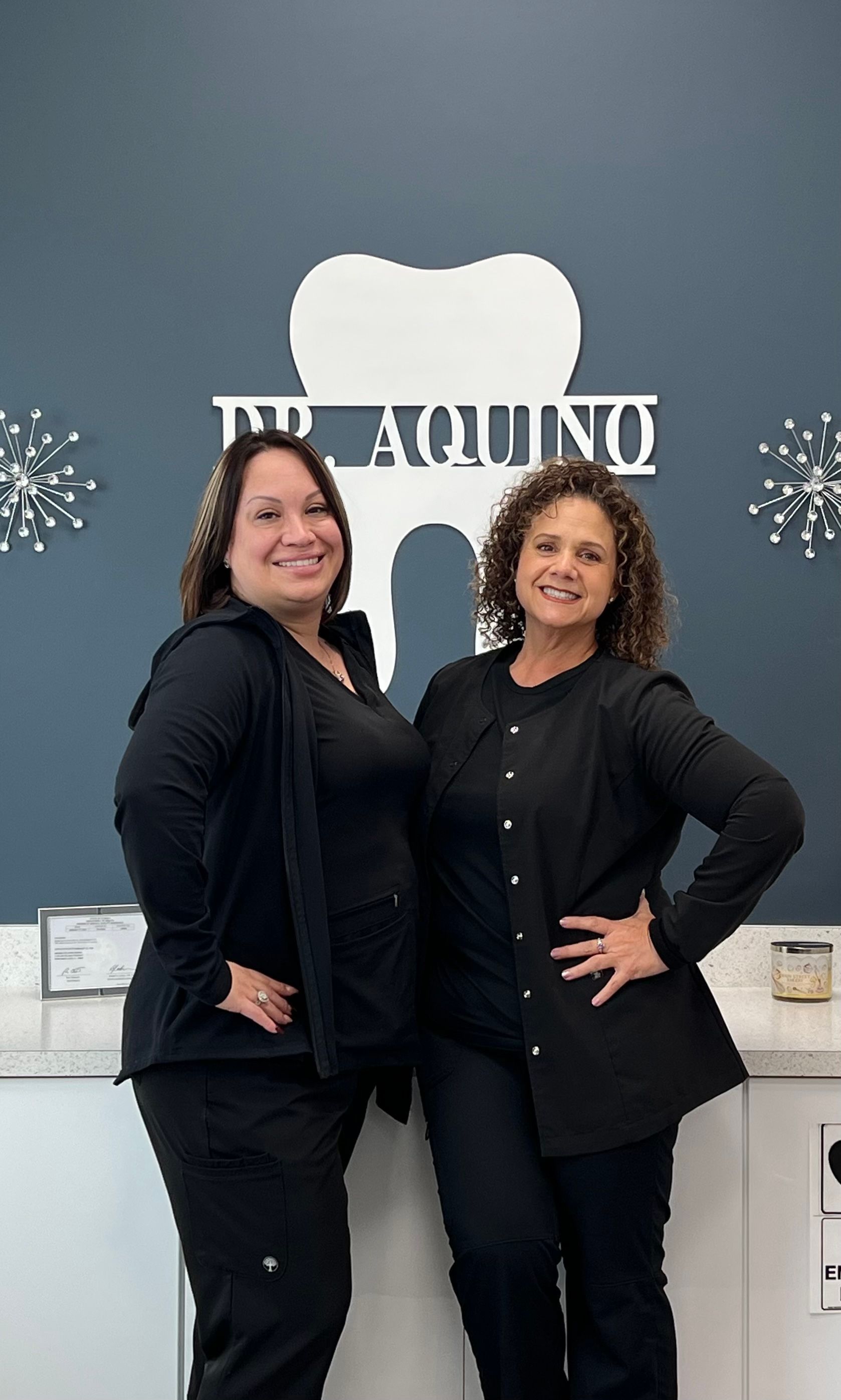 Two women are standing next to each other in front of a dental office.