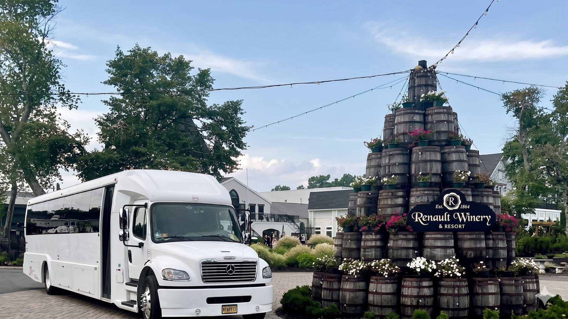 A white shuttle bus parked next to a stacked barrel display with a 
