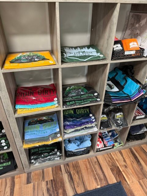 Folded graphic T-shirts stacked in cubby shelves, with wood flooring in a retail display.