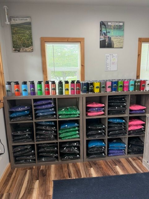 Shelved stacks of folded clothes and colorful drink bottles against a wall in a retail-like room