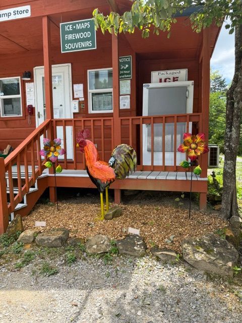 Red wooden porch with a crane sculpture, flowers, and a sign for a tree farm office