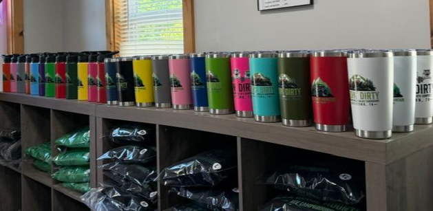 Colorful tumblers lined up on a shelf above cubbies with folded clothes in a room