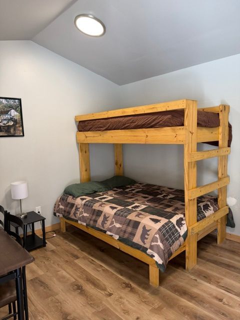 Wooden bunk bed with patterned bedding in a small, bright bedroom.