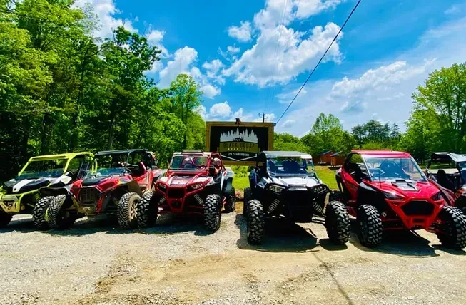 Row of colorful off-road ATVs parked outside under a bright blue sky