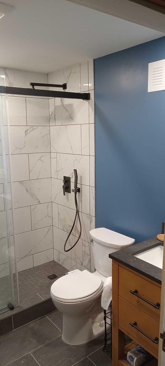 A newly updated small bathroom with blue walls and marble tiles