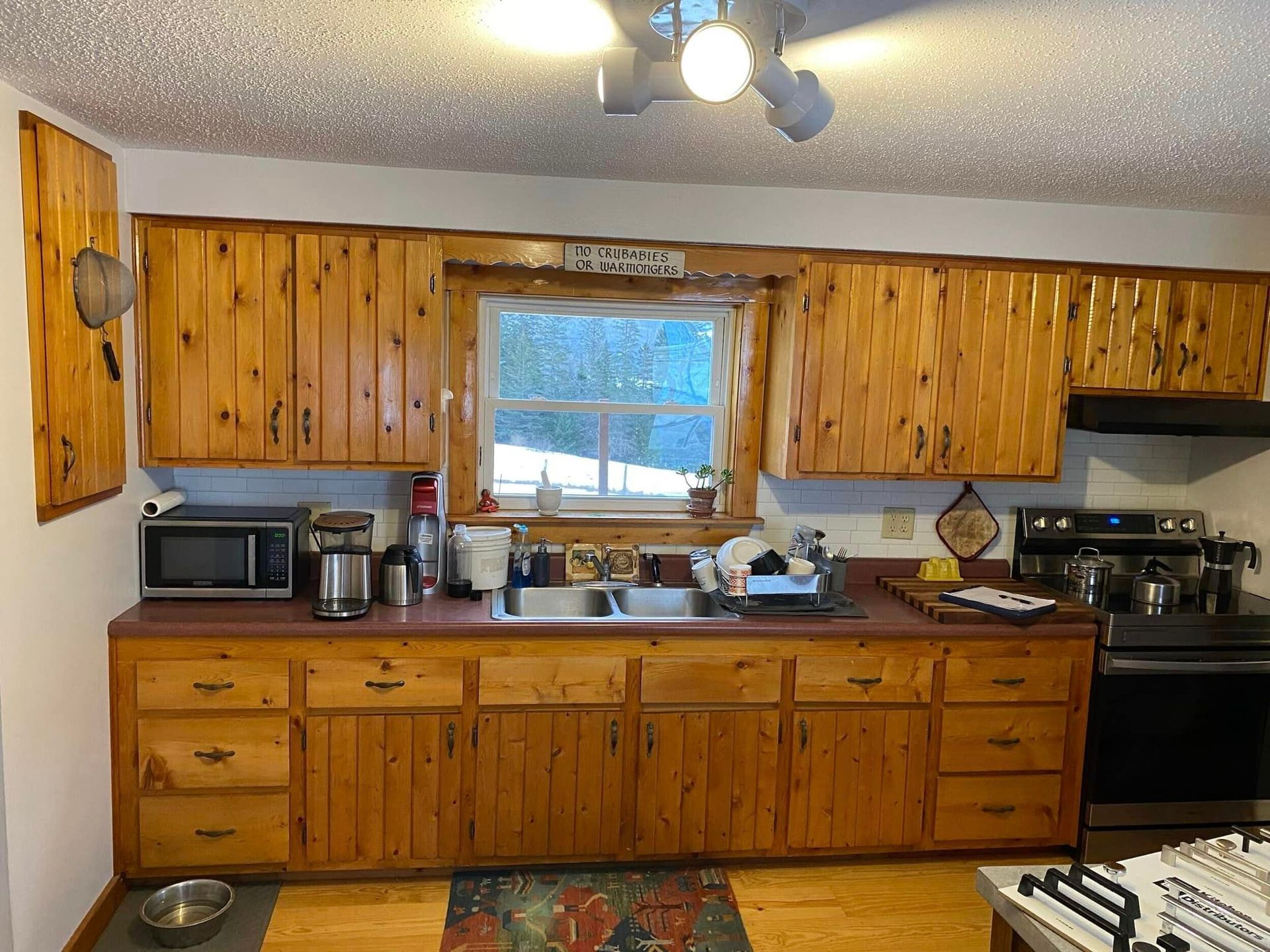 An outdated rustic kitchen with  natural wood cabinets and a laminate counter top