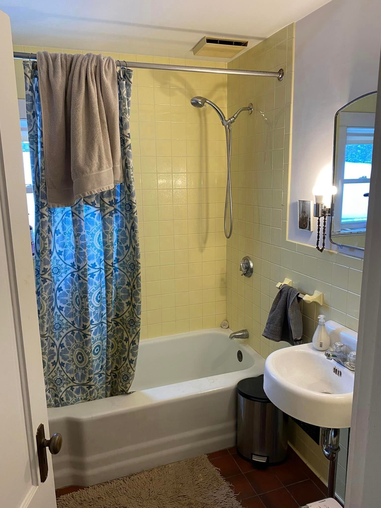 A small, outdated bathroom with yellow tiles and bath tub