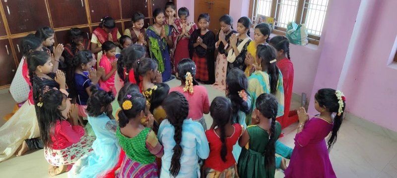 A group of young girls are standing in a circle in a room.